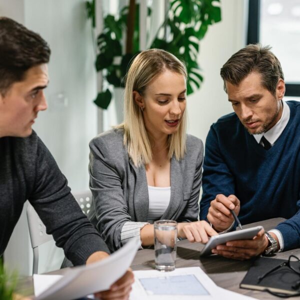 rear-estate-agent-young-couple-going-through-housing-plans-touchpad-while-having-meeting-home_637285-3884